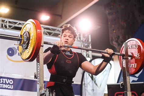 Športovci vykonávajúci drepy s ťažkými váhami v powerliftingu