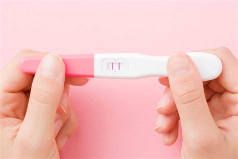 Žena držiaca tehotenský test s pozitívnym výsledkom a antikoncepčné balenie