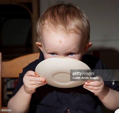 Child licking a plate at home