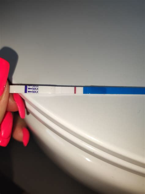 Žena držiaca tehotenský test so slabou čiarkou