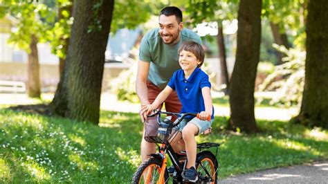 Dieťa učiace sa bicyklovať a spadnúť, zatiaľ čo ho rodič povzbudzuje