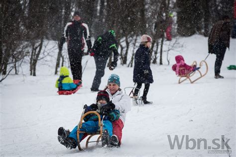 Deti sa sánkujú na zasneženom kopci.