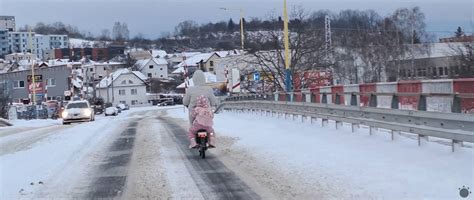 Rodina ťahá dieťa na saniach po zasneženej ceste.