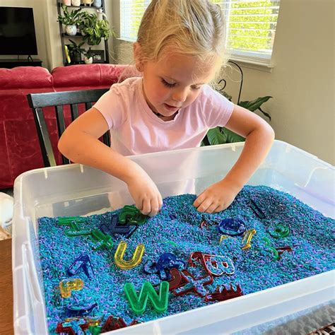Child playing with food in a sensory bin